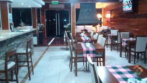 Ein Restaurant mit Barbereich, Holzmöbeln und einem Fernseher an der Wand.