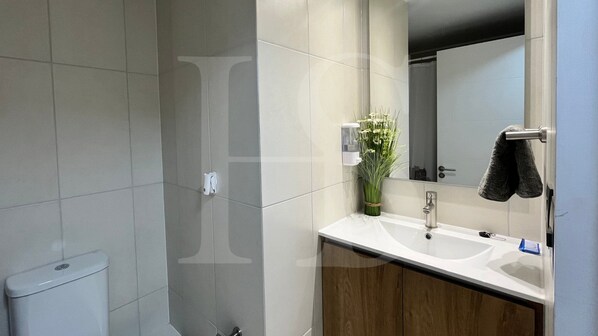 A modern bathroom with a toilet, sink, mirror, and towel rack.