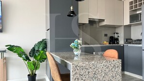 A modern kitchen with a granite countertop, a coffee machine, and a microwave.