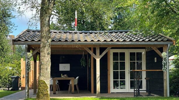 A small, rustic building with a tiled roof and a covered patio area. - 🏡 Detached chalet on the edge of the Veluwe - luxury, sauna, peace & space (Putten)