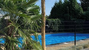 A pool area with a wooden post, palm trees, and a fence. - 🏡 Detached chalet on the edge of the Veluwe - luxury, sauna, peace & space (Putten)