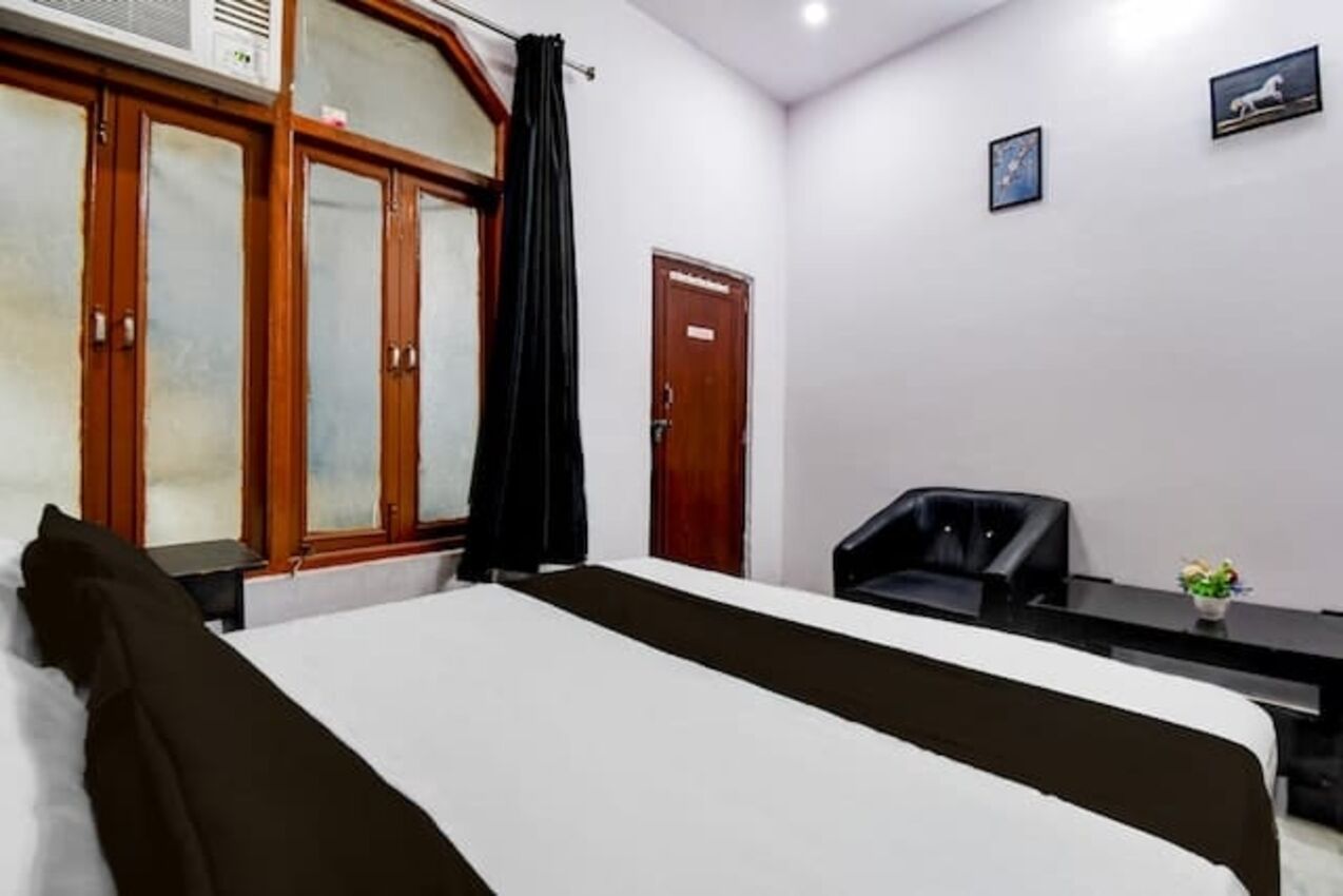 Una habitación de hotel con cama, escritorio, silla, armario y puerta.