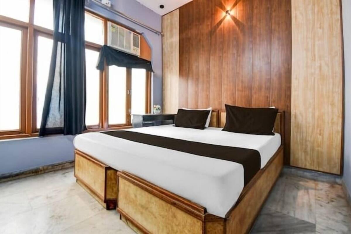 Une chambre moderne avec un grand lit, une tête de lit en bois et une fenêtre avec des rideaux.