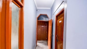A narrow hallway with wooden doors and a marble floor. - HOTEL STAY INN (Lucknow)