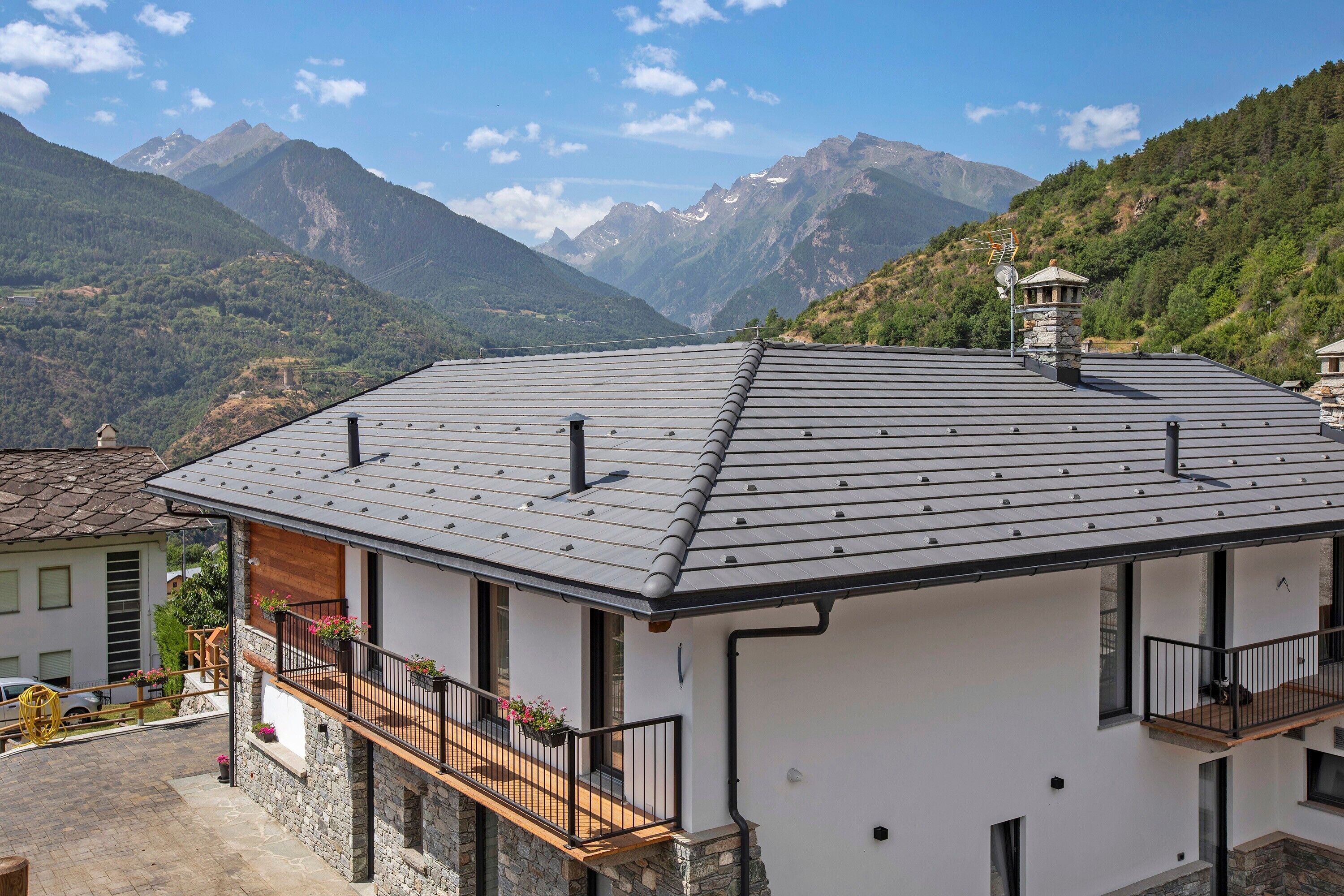 A modern building with a sloped roof, stone foundation, and balconies with railings.