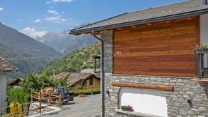 A mountain lodge with stone and wooden exterior, a car parked outside, and a view of the surrounding mountains. - 'Golden' Room with Mountain View, Wi-Fi and Air Conditioning (Saint-Pierre)