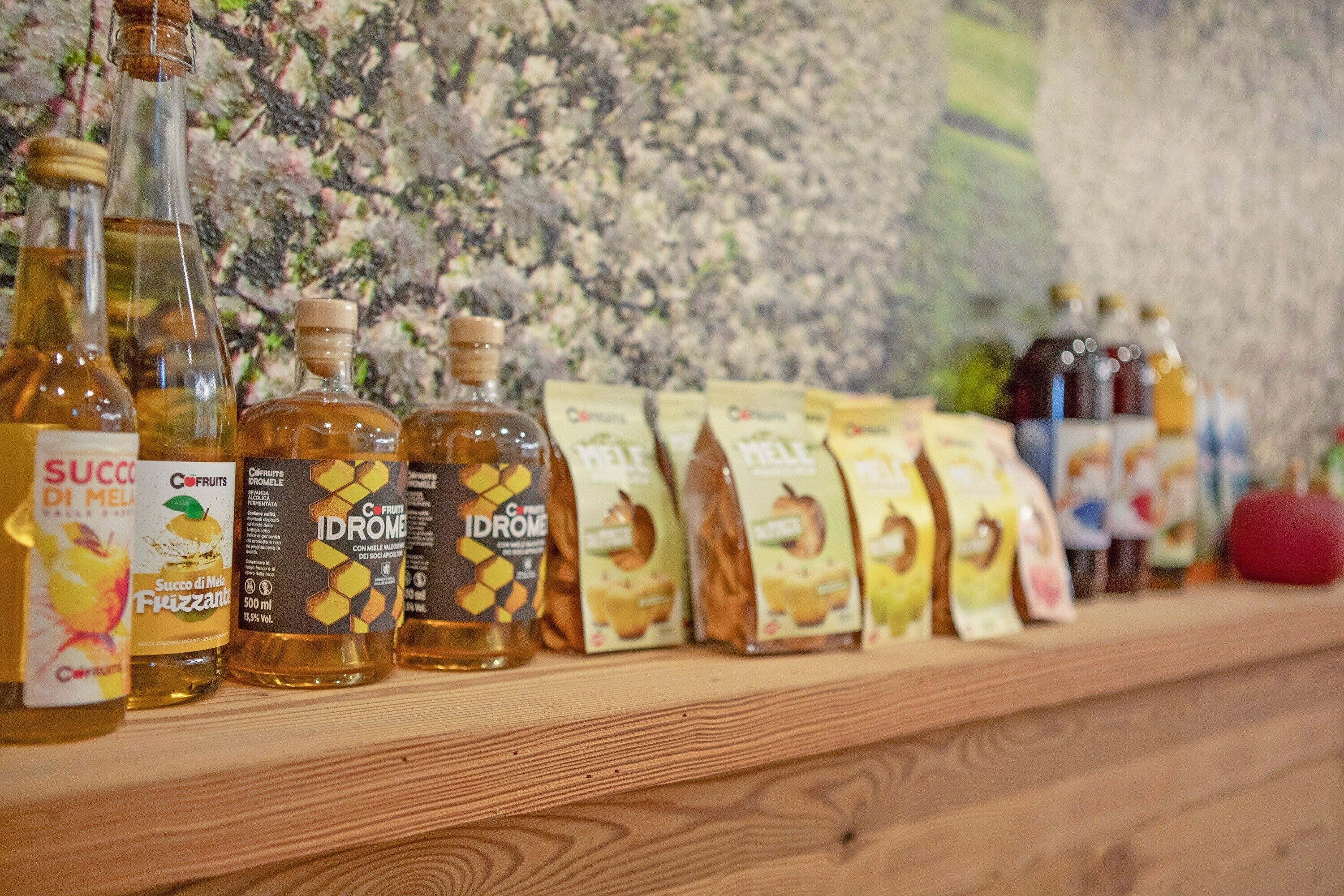 Un estante de madera con varias botellas y paquetes de miel y otros condimentos.