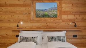 A wooden-paneled room with a bed, pillows, a framed picture, and wall-mounted lights. - 'Golden' Room with Mountain View, Wi-Fi and Air Conditioning (Saint-Pierre)