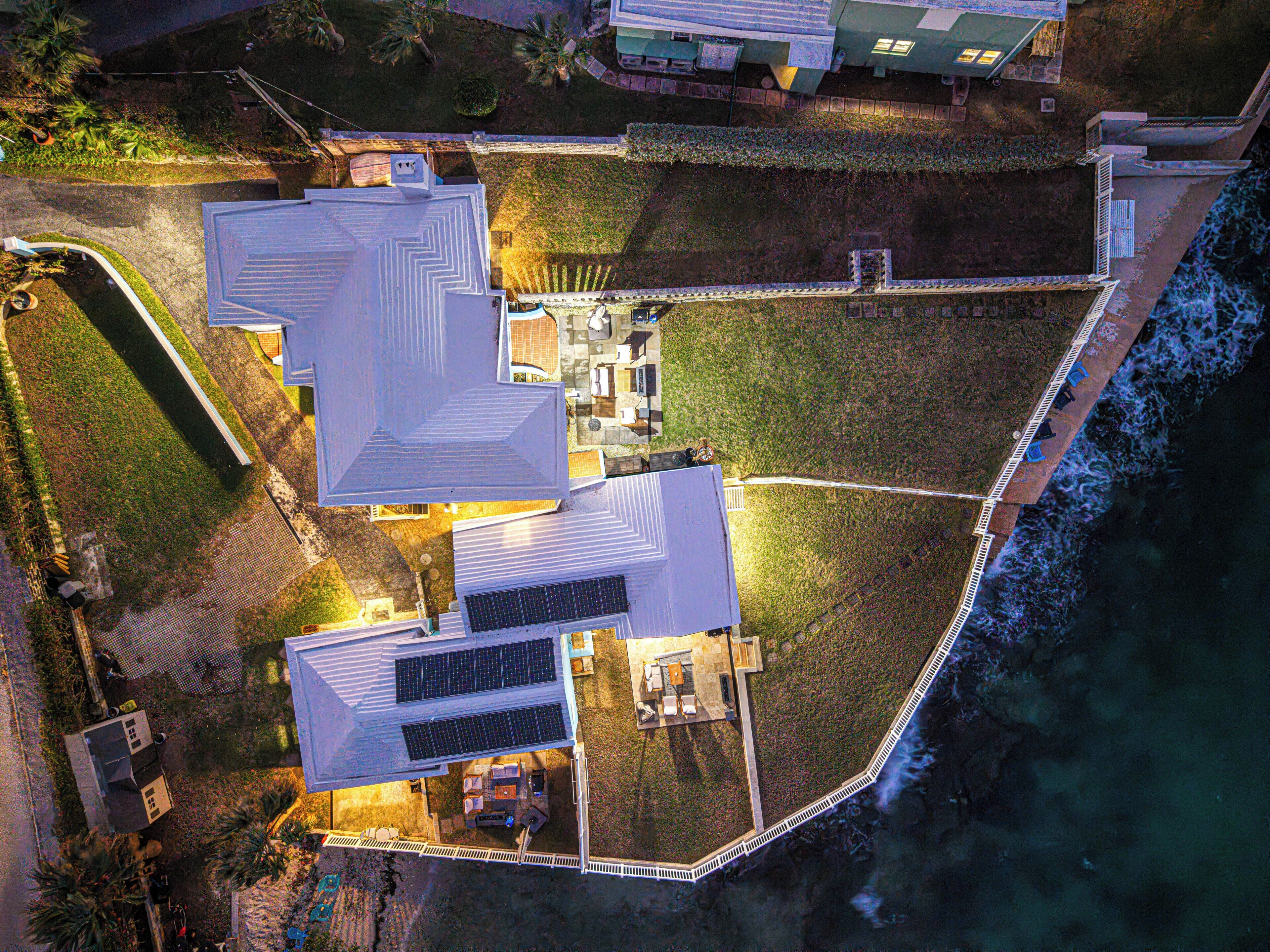 Luchtbeeld van een landgoed met een groot huis, een kleinere aanbouw en een omheinde tuin.