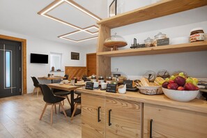 Une cuisine moderne avec des meubles en bois, un coin repas avec des chaises et un panier de fruits posé sur le comptoir.
