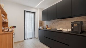 Una cucina moderna con mobili scuri, una macchina da caffè e un bancone in legno con utensili da cucina.