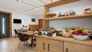 Una cucina moderna con mobili in legno, una zona pranzo con sedie e una ciotola di frutta sul piano di lavoro.