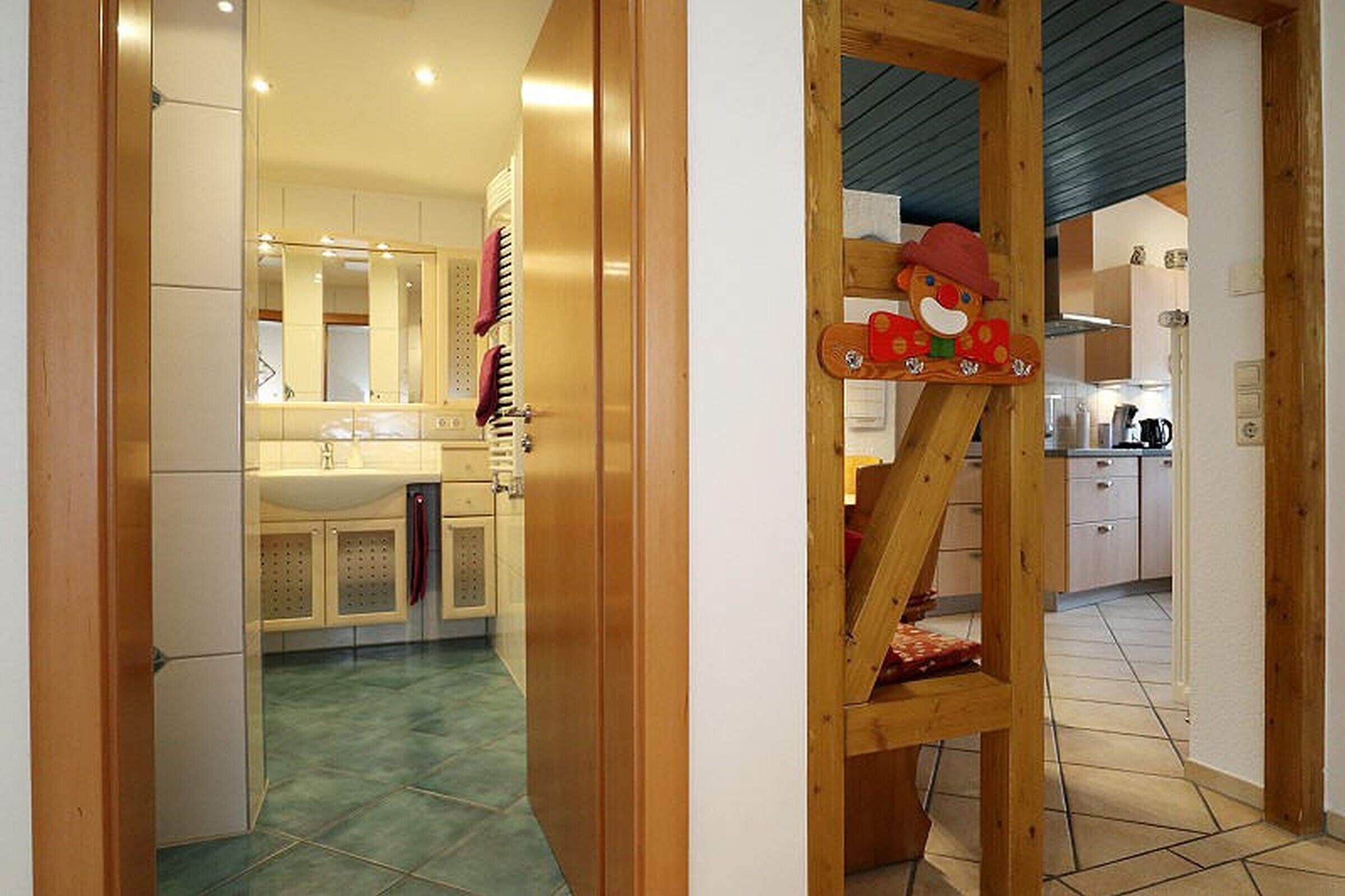 A kitchen with a wooden staircase, a sink, cabinets, and a mirror.