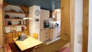 A kitchen with wooden cabinets, a clock, and a dining area with a table and chairs.