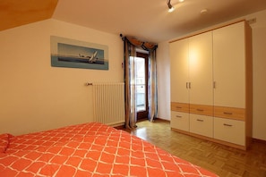 Ein Schlafzimmer mit Bett, Heizkörper, Kleiderschrank und einem Bild an der Wand.