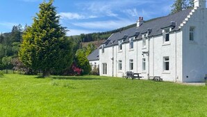 A white building with a flat roof, multiple windows, and a grassy lawn in front. - Spacious Argyll Farmhouse in an Idyllic Setting (Dunoon)