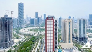 Un edificio de gran altura con un diseño arquitectónico moderno, rodeado de otros edificios altos y grúas de construcción, lo que indica una zona de desarrollo urbano.