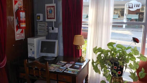 Une pièce avec un bureau, un ordinateur et une fenêtre avec des rideaux.