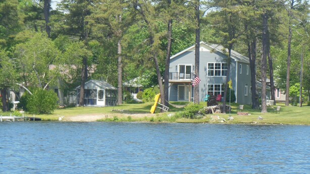 A lakeside house with a dock, a small boathouse, and a flag.