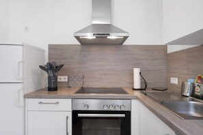 A kitchen with a built-in oven, a stainless steel range hood, and a wooden countertop.