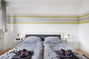 A twin room with two beds, bedside tables, lamps, and a view of the street.