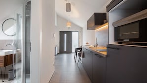 A modern kitchen with a built-in oven, a glass shower enclosure, and a minimalist design.