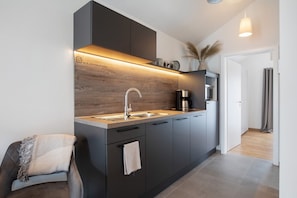 Una cocina moderna con horno empotrado, cafetera y salpicadero de madera.