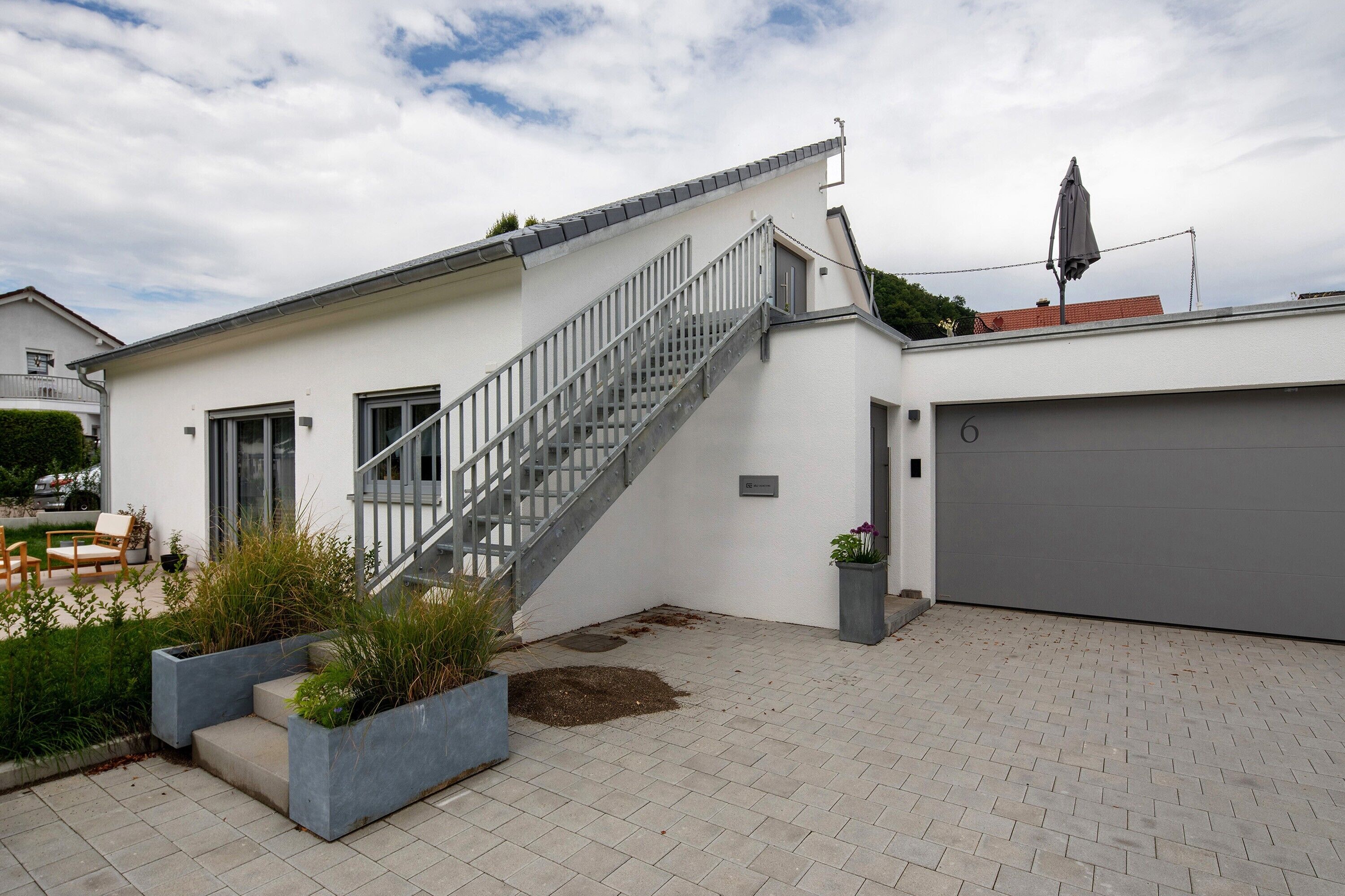 Et moderne hus med trappe, garage og en have med plantekasser.