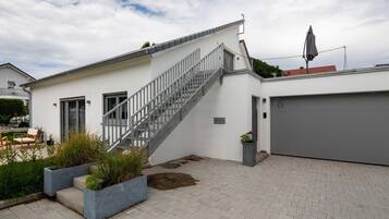 Et moderne hus med trappe, garage og en have med plantekasser.