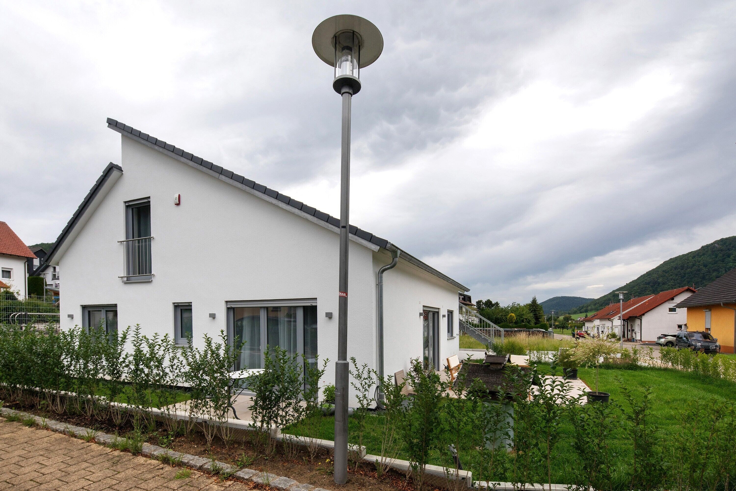 Un edificio moderno blanco con techo plano, una ventana visible y una farola.