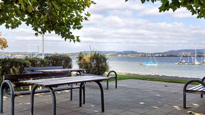 A waterfront park with benches, a view of the water, and sailboats. - Apartment 'Kajüte Without Balcony' with Lake View, Shared Terrace and Wi-Fi (Moos)