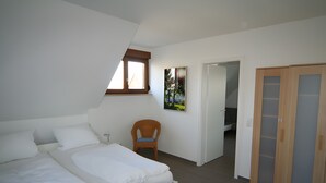 A bedroom with a bed, a chair, a wardrobe, and a door leading to another room. - Apartment 'Kajüte Without Balcony' with Lake View, Shared Terrace and Wi-Fi (Moos)