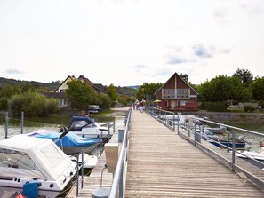 Une jetée en bois s’étendant dans une étendue d’eau calme, avec des bateaux amarrés de chaque côté.