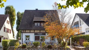 Un bâtiment traditionnel avec un toit en tuiles, un escalier en pierre et une enseigne sur laquelle on peut lire « PERLUSCHEL ».