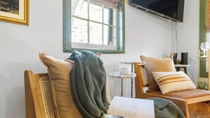 A cozy room with a wooden chair, a small table with a book and a cup, and a window with blinds.