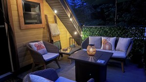 Een terras buiten met rieten meubels, een tafel en een wandlamp.