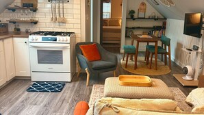 Een knus woongedeelte met een kitchenette, een eethoek en een zithoek met een bank en stoelen.