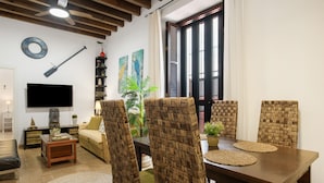Una sala de estar con televisor, sofá, mesa de comedor, sillas y ventilador de techo.