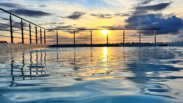 A swimming pool with a sunset view, surrounded by a metal fence. - Chic 1-bedroom apartment with AC, WiFi in fabulous Flic en Flac (Flic en Flac)