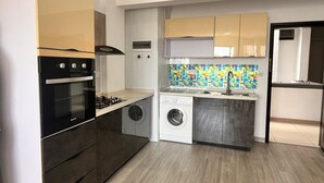 A compact kitchen with a stove, oven, washing machine, and a tiled backsplash. - Chic 1-bedroom apartment with AC, WiFi in fabulous Flic en Flac (Flic en Flac)