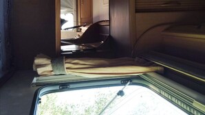 A narrow interior space with a window, a door, and a bench. - Uljanas Caravana for 2 With View of the Rescued Horses (Lagos)