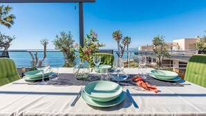Mesa posta para refeição com vista para o mar, assentos ao ar livre e céu claro.
