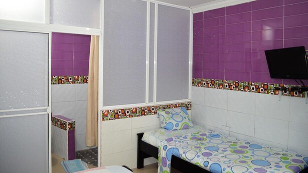 A small, private room with a bed, a TV, and a window with a curtain. - Posada Cocos Place (San Andrés)
