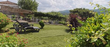 Um gramado bem cuidado com móveis de jardim, um muro de pedra e vegetação exuberante.
