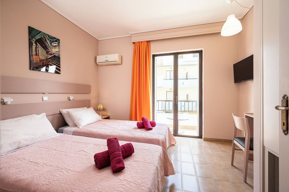 Habitación de hotel con dos camas, televisión, balcón y un cuadro en la pared.