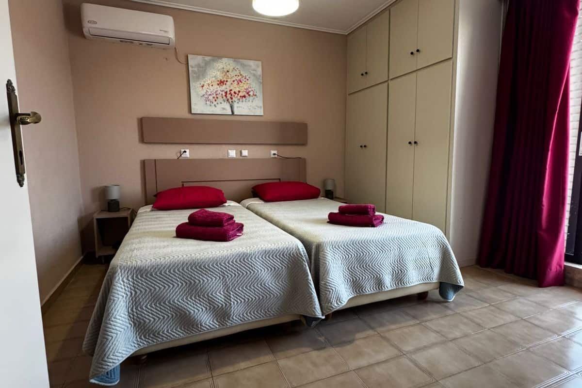 Habitación de hotel con dos camas, una lámpara en el techo, aire acondicionado, un cuadro y un armario.