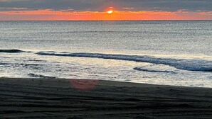 A beach with waves and a sunset.