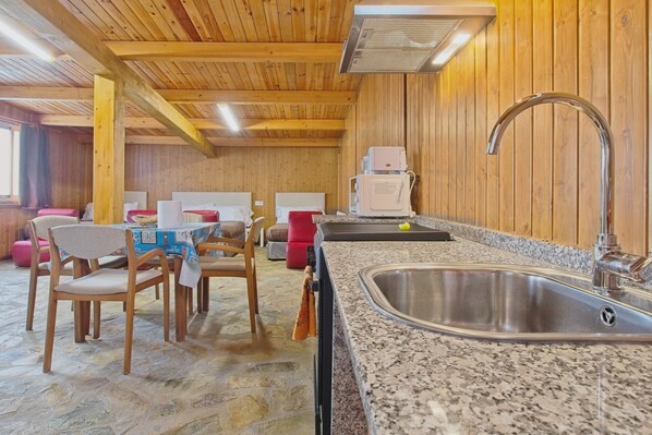 Un interior de madera con encimera de granito, pileta de acero inoxidable y comedor con sillas y mesa.