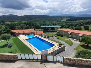 A pool area with a stone wall, a red-roofed building, and a view of the surrounding landscape. - Room 'Casa Jardín Habitación Triple L' with Private Pool, Shared Terrace and Shared Garden (Monforte de Lemos)