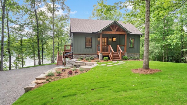 Une cabane avec des fondations en pierre, une terrasse en bois et un escalier menant à l’entrée.